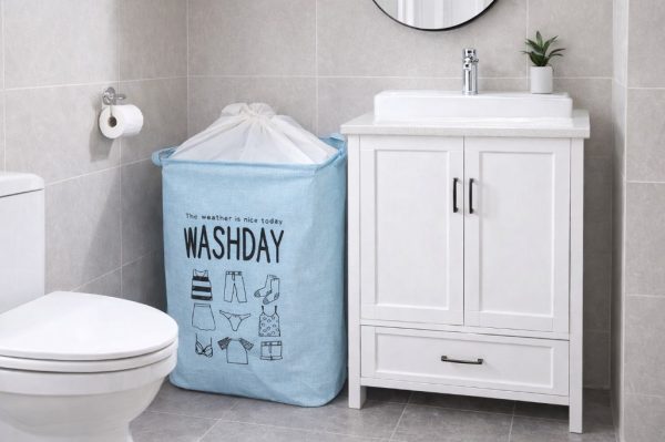 Sklopiva plava korpa za veš sa natpisom Washday u malom kupatilu pored ormarića i WC šolje